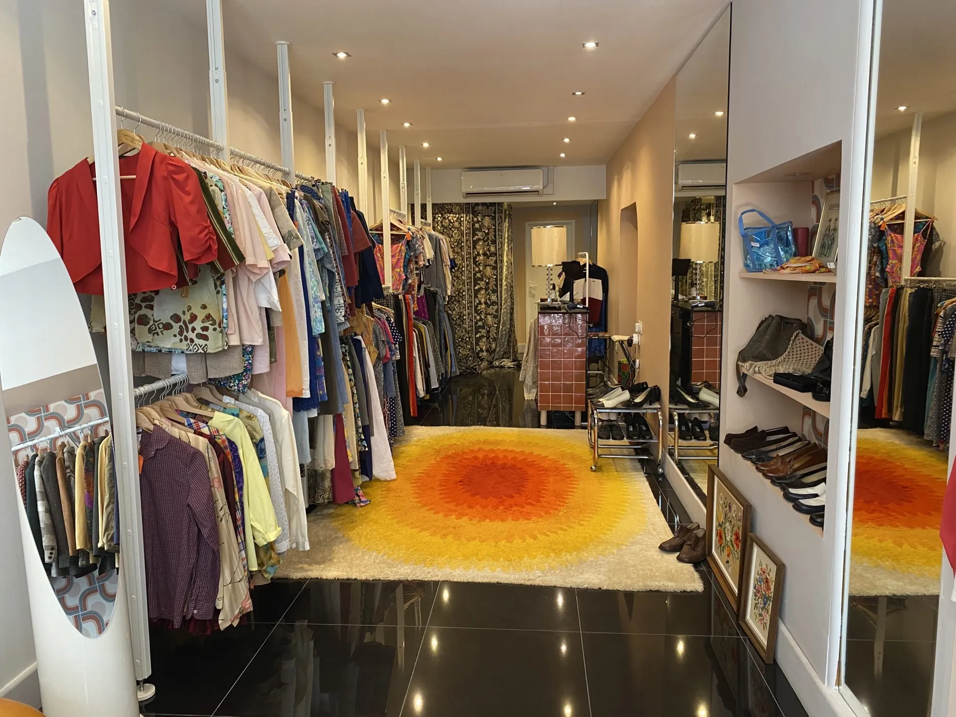 Intérieur de la boutique Jeans Toniques avec portants, chaussures et tapis vintage